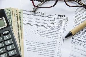 表格1120纳税申报单，包括笔、眼镜、计算器和钱